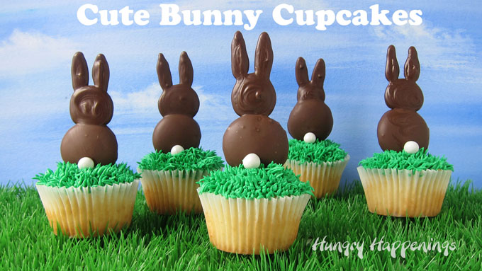 Five cute bunny cupcakes sitting on top of grass in front of a blue sky backdrop look so cute for Easter dessert. 