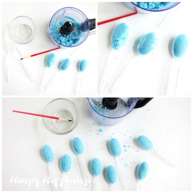 brush corn syrup on a plastic spoon then scoop up some of the blue sugar mixture and press down on it using another spoon that is facing the opposite direction to create sugar spoons that can be dipped in coffee or hot tea