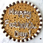 giant chocolate chip cookie cake decorated with white marshmallow frosting and chocolate frosting with 