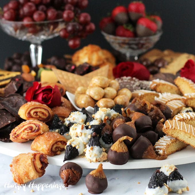 a beautiful display of desserts including chocolate dipped figs, cookies, fruit, and more