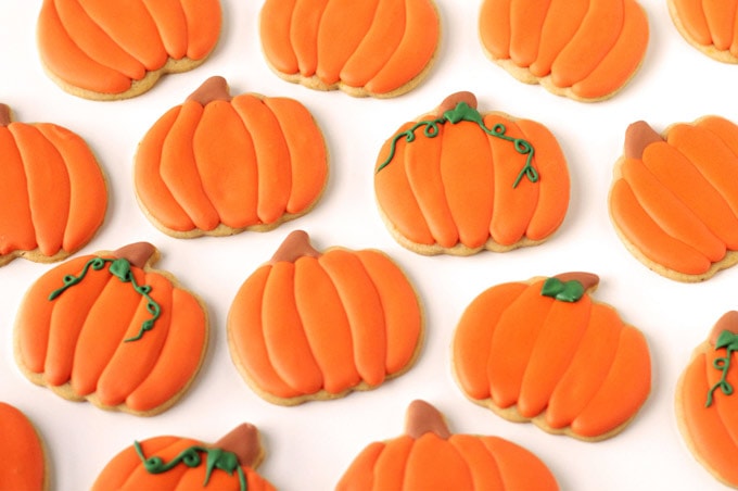 Pumpkin shaped cut-out-cookies decorated with orange royal icing. 