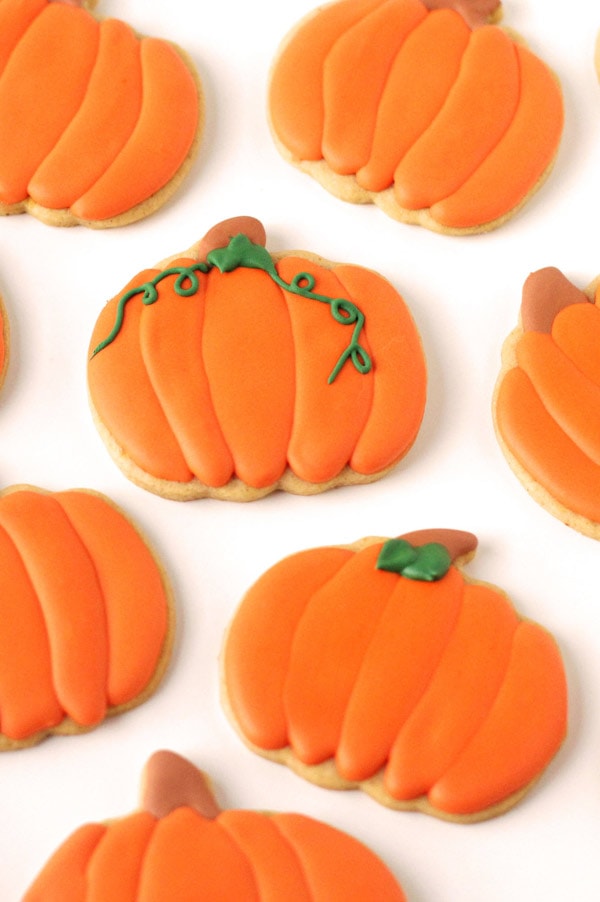 Maple flavored royal icing is used to decorate pumpkin shaped pumpkin spiced cut-out cookies. 