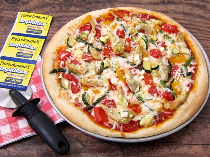 Top a homemade pizza crust with roasted vegetables and marinated artichokes and mozzarella & feta cheese. 