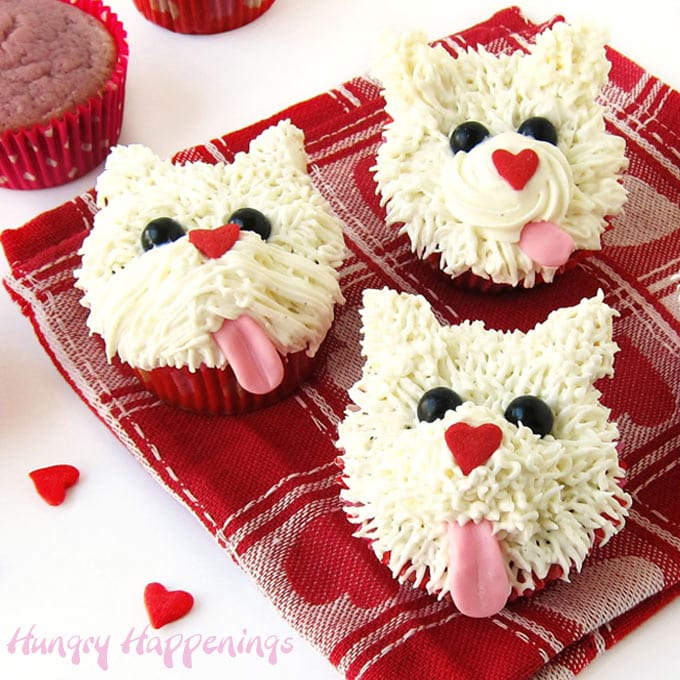 white puppy dog cupcakes with pink tongues and heart shaped noses next to raspberry cupcakes