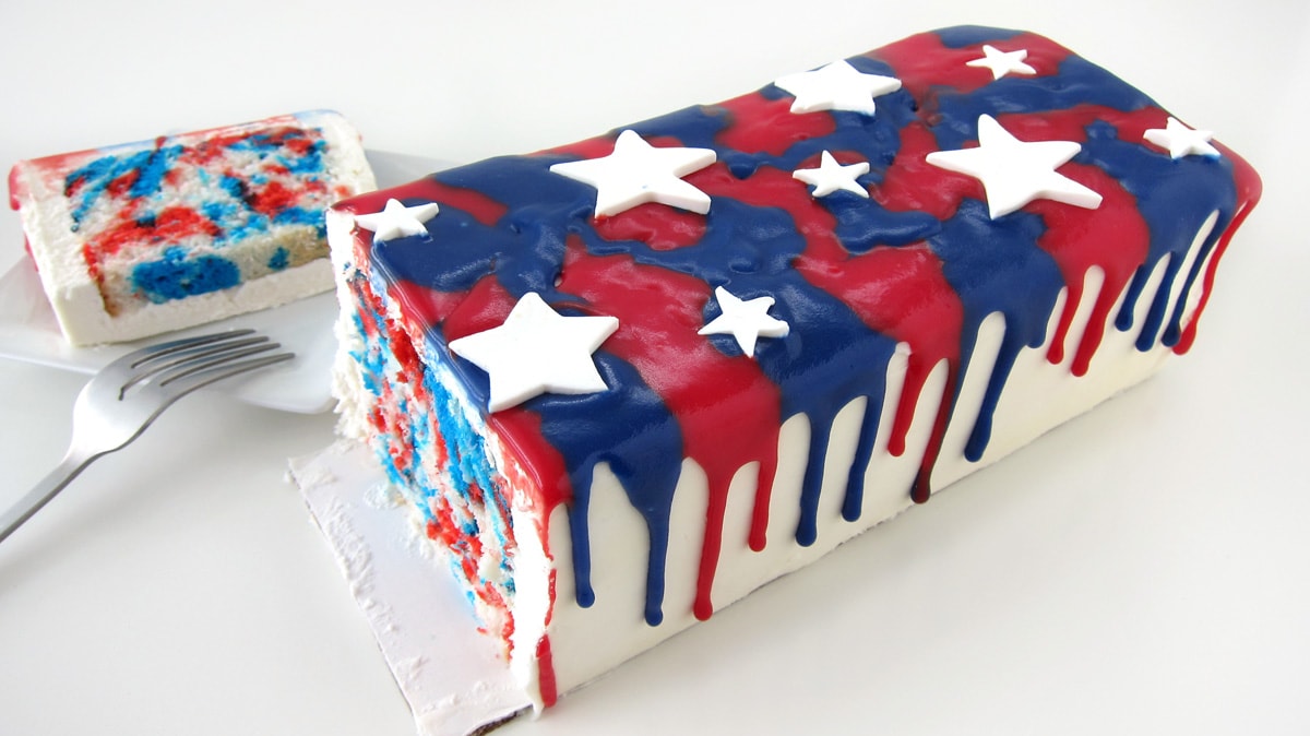 White modeling chocolate stars on top of a red, white, and blue drip cake. 