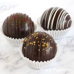 dark chocolate hot cocoa bombs drizzled with chocolate and topped with edible glitter or sprinkles
