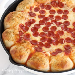 Pizza dip baked in a skillet surrounded by cheese-filled pizza crust topped with a sprinkling of parmesan cheese bread dip seasoning.