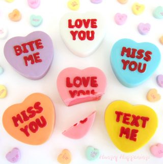 conversation heart truffles are decorated with phrases like "love you," "miss you," "text me," and "bite me" and are filled with colorful white chocolate ganache