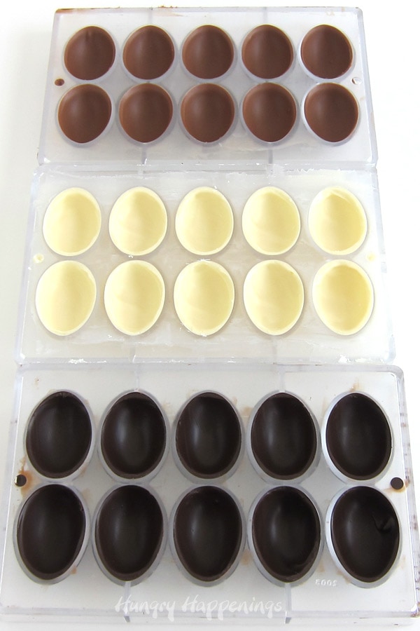 Egg-shaped milk chocolate, white chocolate, and dark chocolate hot chocolate bomb shells.