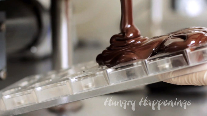 pouring tempered chocolate into a candy mold
