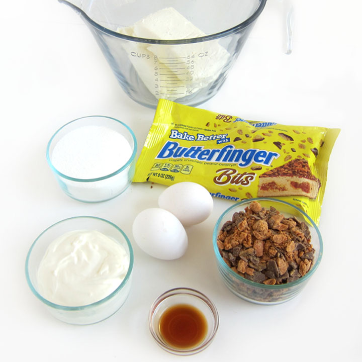 Ingredients to make Butterfinger Cheesecakes including cream cheese, sugar, sour cream, eggs, vanilla, and Butterfinger Baking Bits.