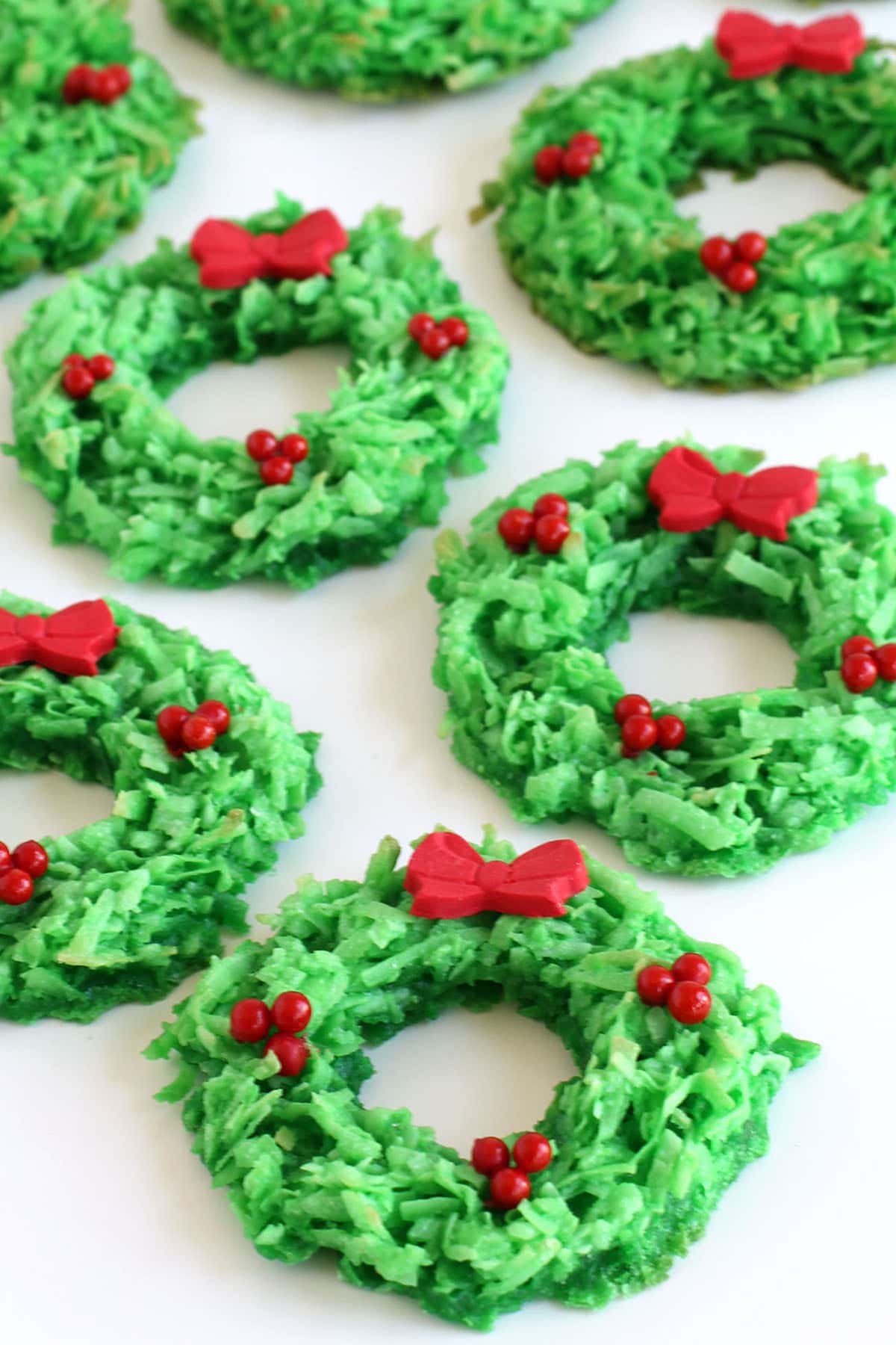 Coconut Macaroon Wreaths decorated with red sugar pearls and red modeling chocolate bows.