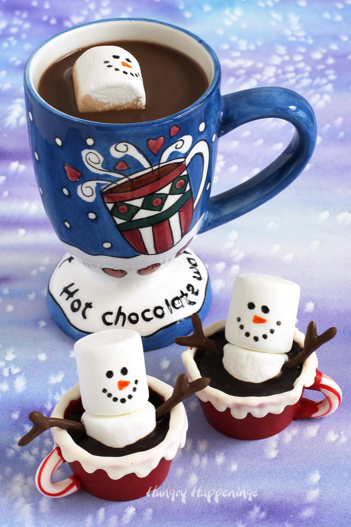 Snowmen Hot Chocolate Bombs with a marshmallow snowman floating in a mug of hot cocoa.
