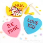 breakable chocolate conversation hearts filled with Valentine's Day candy smashed with a wooden mallet