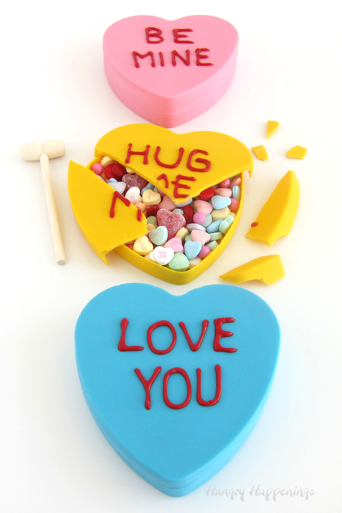 pink, yellow, and blue white chocolate conversation hearts with one broken open revealing Valentine's Day candy inside