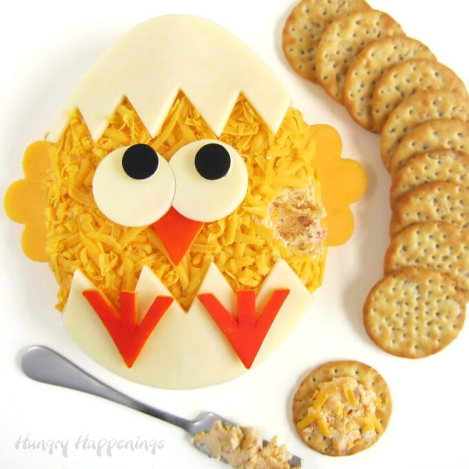 Easter cheese ball hatching chick decorated with cheese slices and served with crackers.