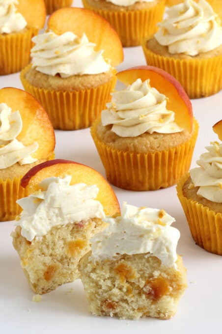 peach cupcakes loaded with fresh peaches are topped with peach-flavored whipped cream frosting