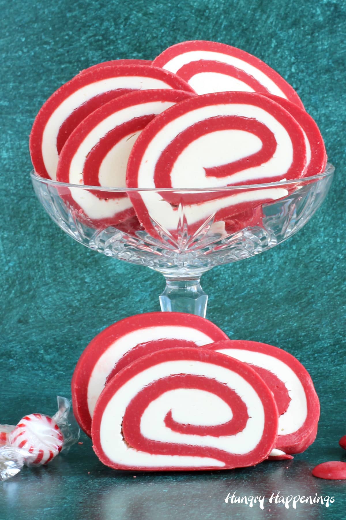 Red and white peppermint fudge pinwheels in candy dish next to starlight mints and red candy melts