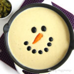 queso blanco snowman decorated with black olive eyes and a carrot nose
