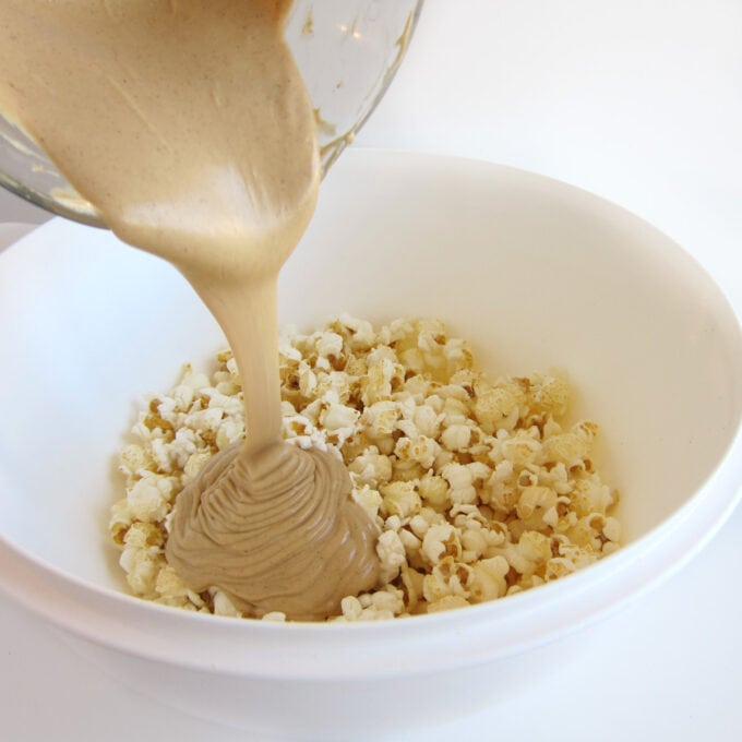 pouring melted peanut butter topping over popcorn