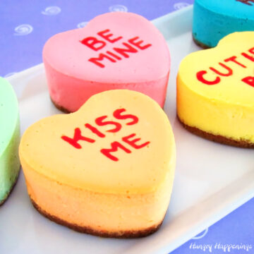 Conversation heart cheesecakes on a white plate with a puple background