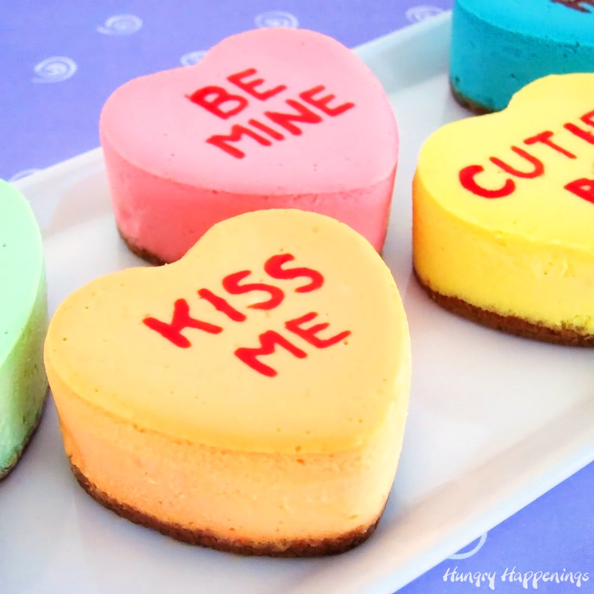 Conversation heart cheesecakes on a white plate with a puple background