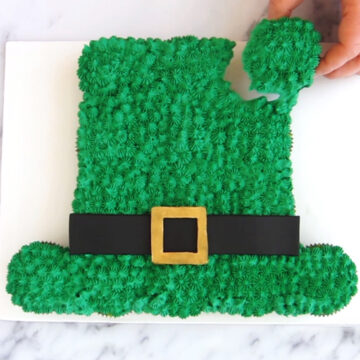 Leprchaun hat cupcake cake decorated with green frosting stars, a black and gold hat band