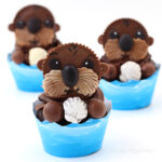 Reese's cup sea otter cupcakes holding candy shells sitting in blue wave cupcake wrappers