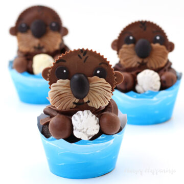 Reese's cup sea otter cupcakes holding candy shells sitting in blue wave cupcake wrappers