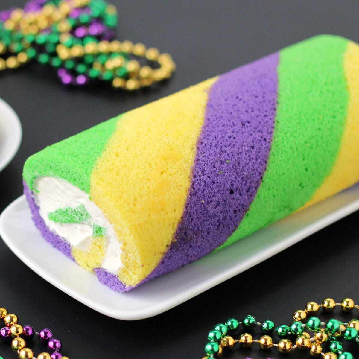 Mardi Gras King Cake Roll with gold, green, and purple beads