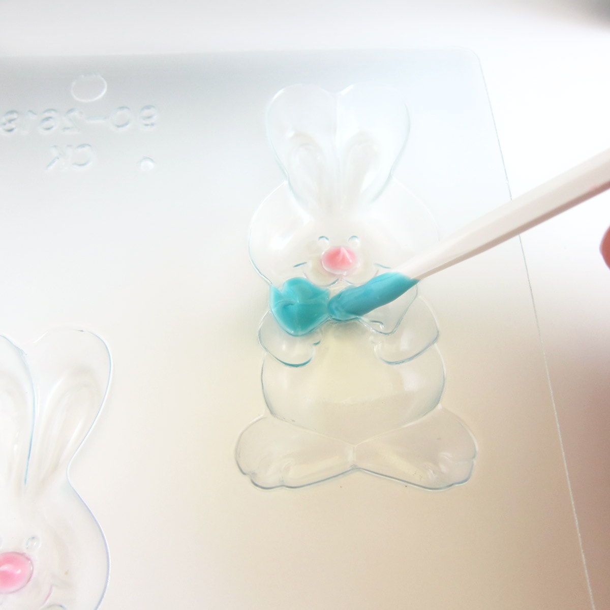 painting a blue bowtie in a bunny candy mold