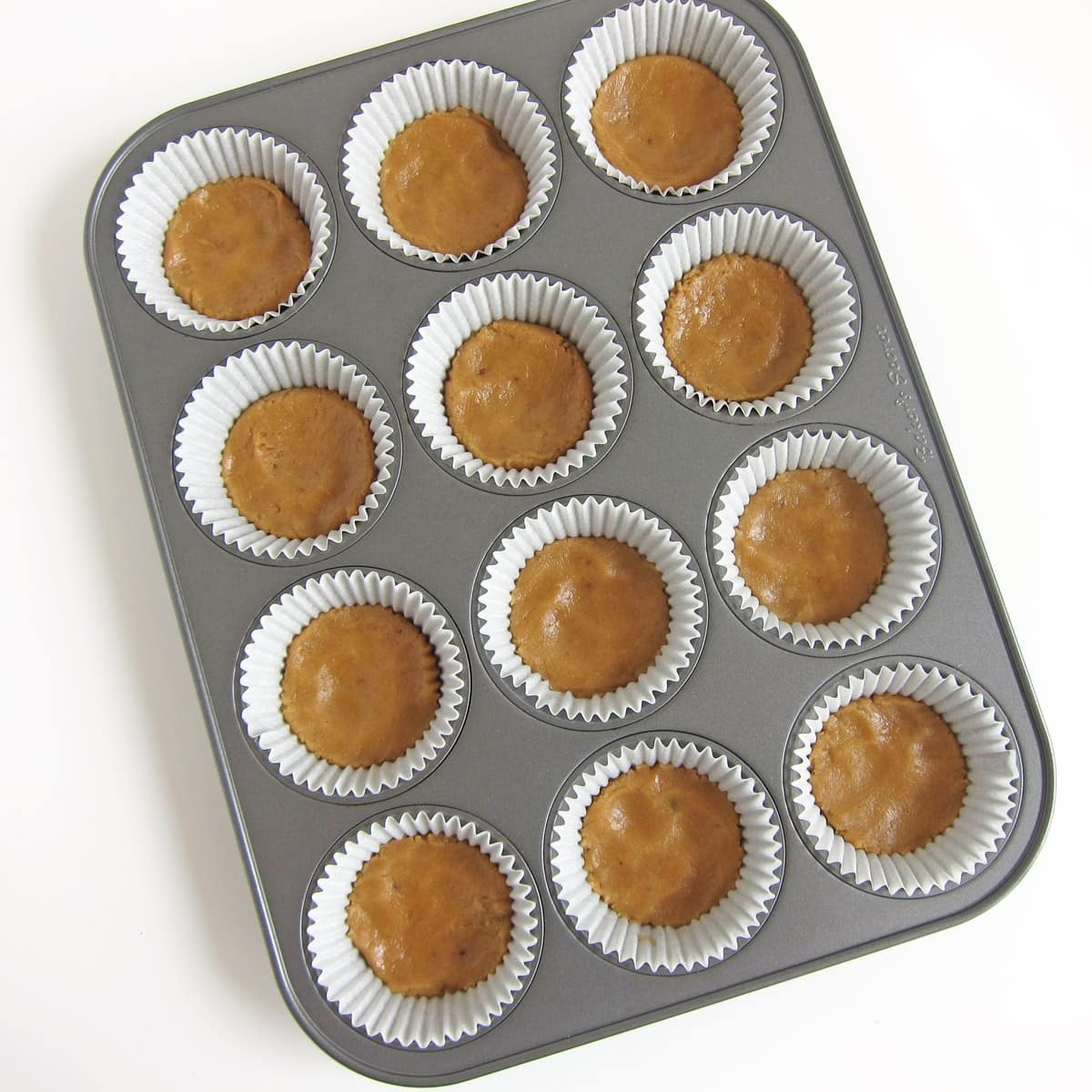 Unbaked peanut butter cookie dough in cupcake pan. 