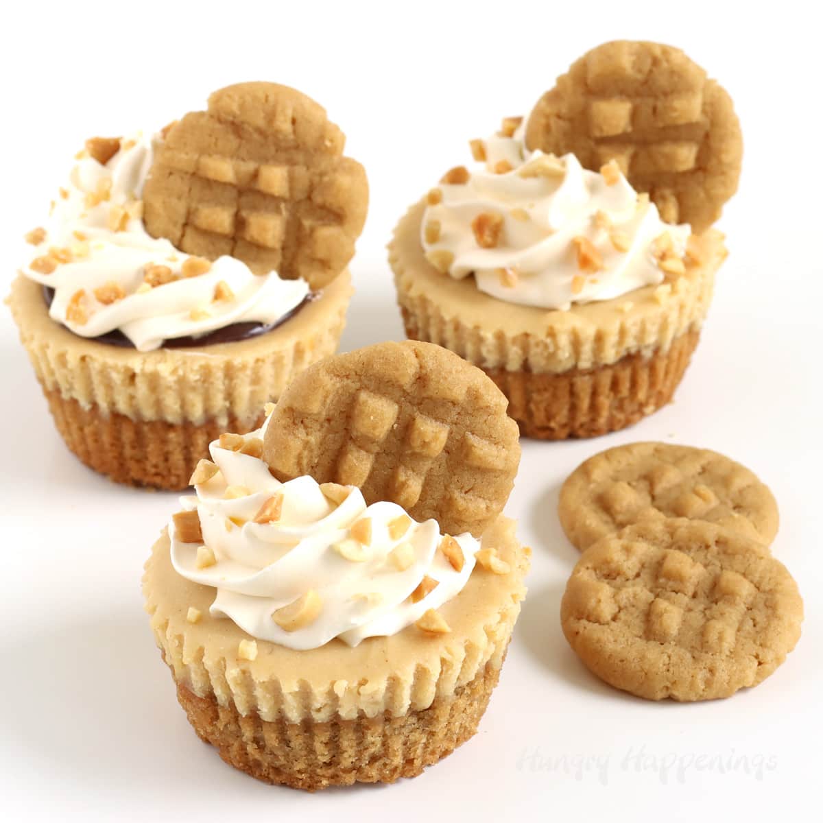 Mini peanut butter cheesecakes topped with whipped cream, chopped nuts, and mini peanut butter cookies.