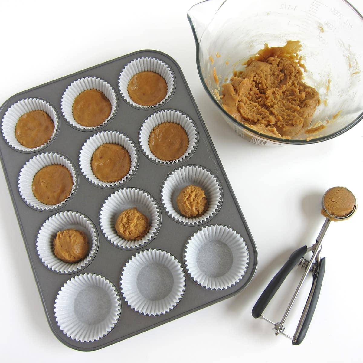 Cookie dough scoops in cupcake wrappers in a cupcake pan.