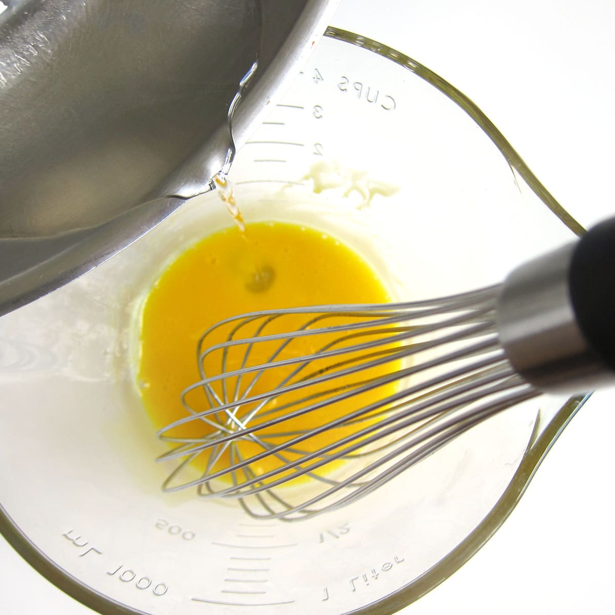 pouring sugar syrup into beaten egg yolks