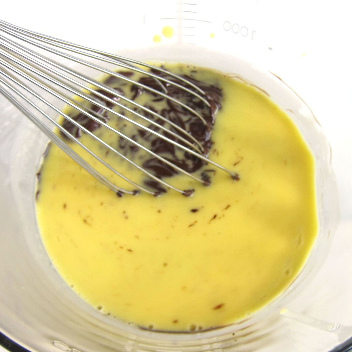 stirring the egg custard into melted chocolate using a whisk