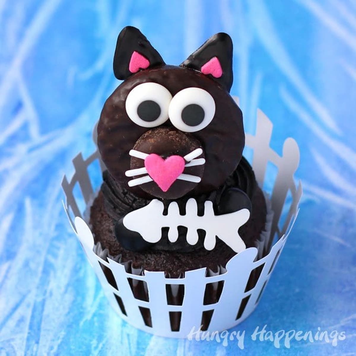 black cat cupcakes with Peppermint Patty cats served in a picket fence cupcake wrapper and decorated with white chocolate fish bones.