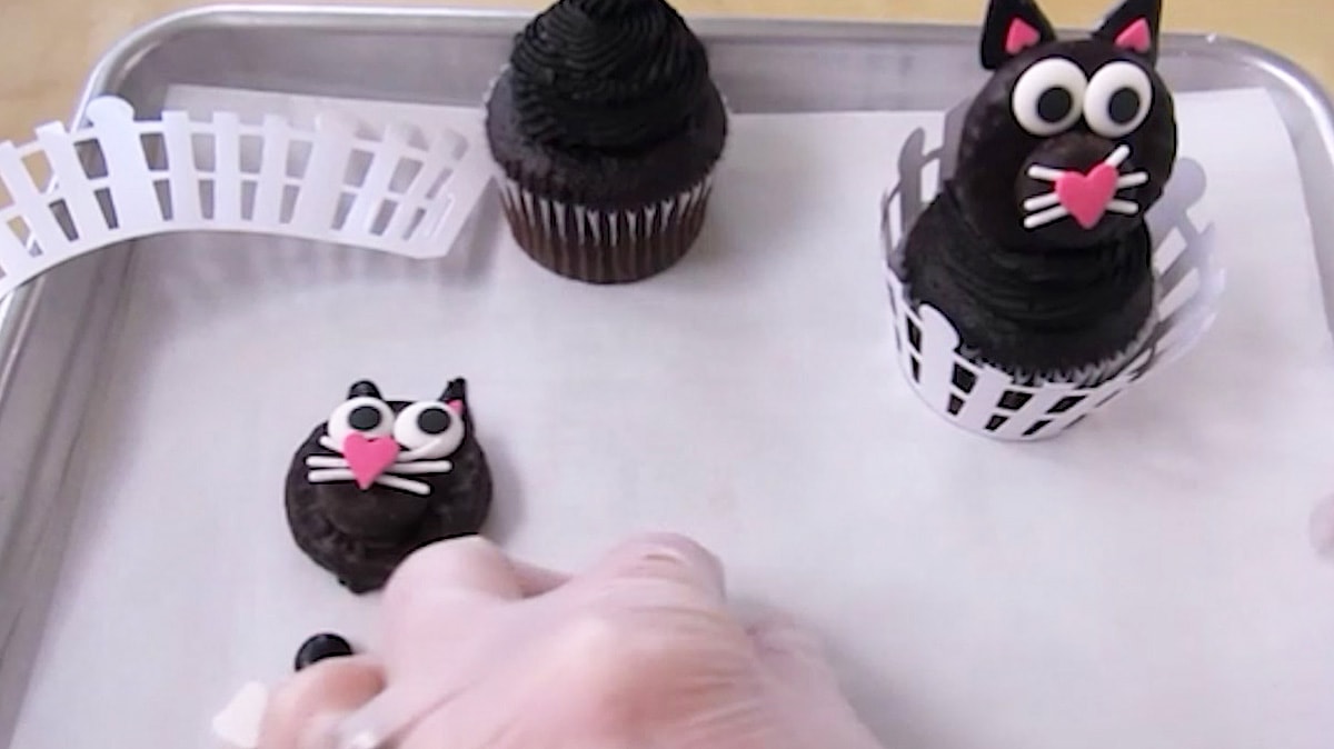 Peppermint Patty black cat set on a chocolate cupcake topped with a swirl of black frosting.