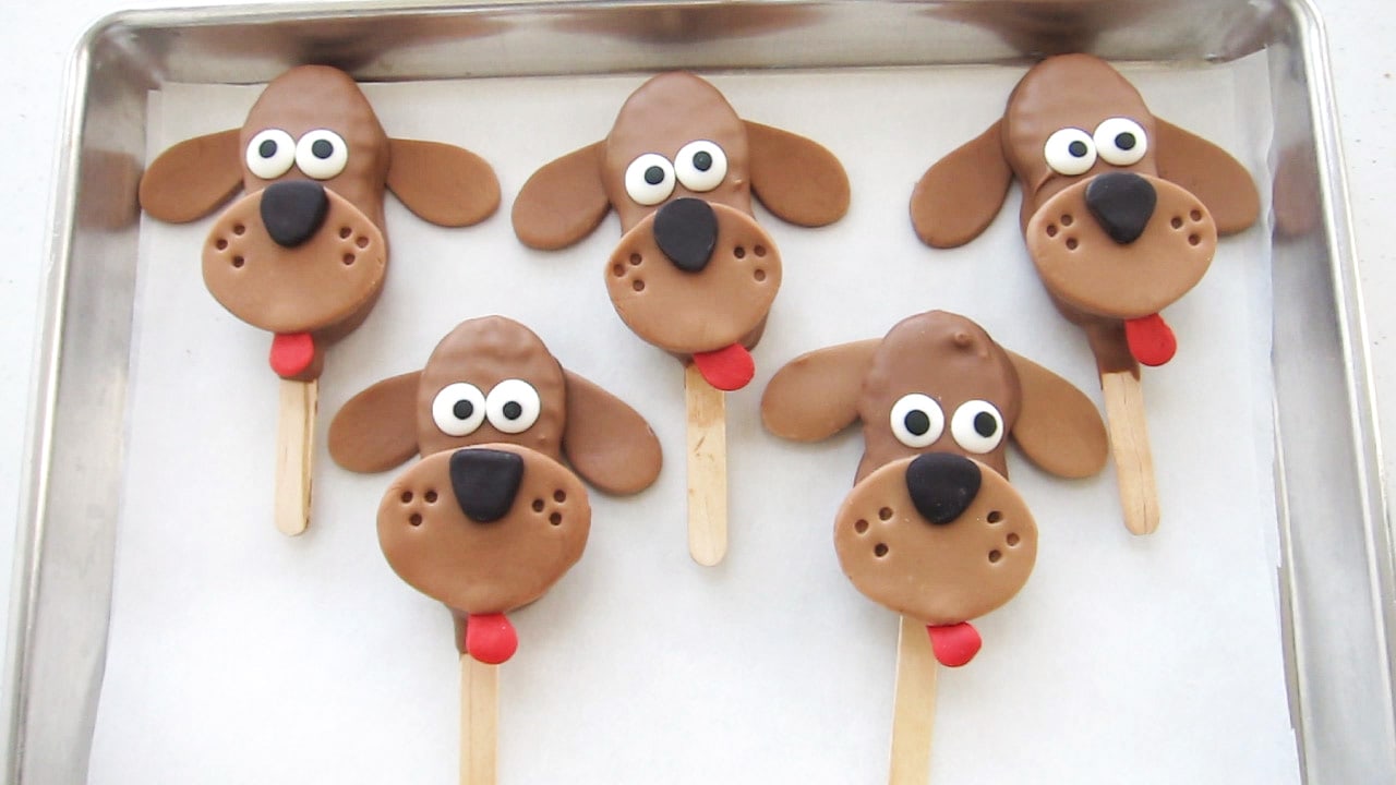 five chocolate dogs set on a parchment paper-lined baking sheet.