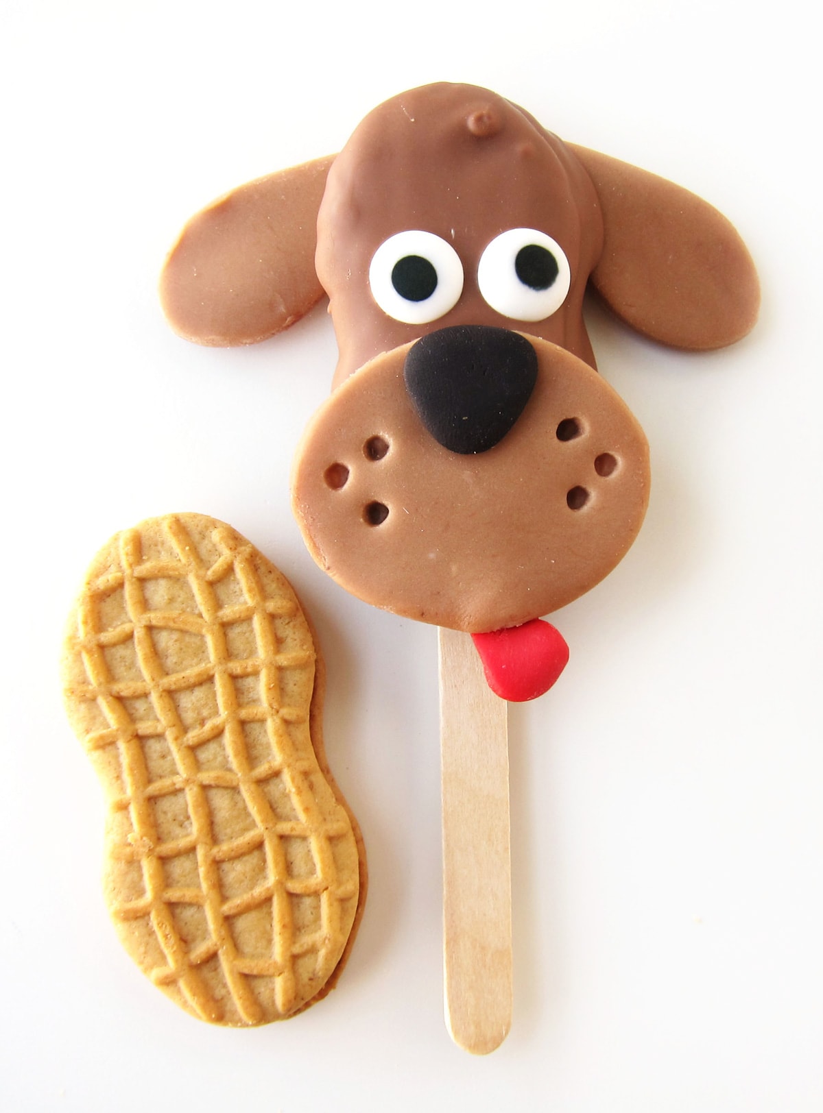 a Nutter Butter Cookie next to a chocolate dog lollipop decorated with candy eyes and a modeling chocolate snout, nose, and tongue.