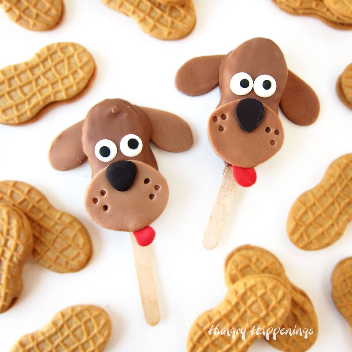 chocolate dogs made from chocolate-dipped Nutter Butter Cookies decorated with modeling chocolate and candy eyes are surrounded by plain cookies.