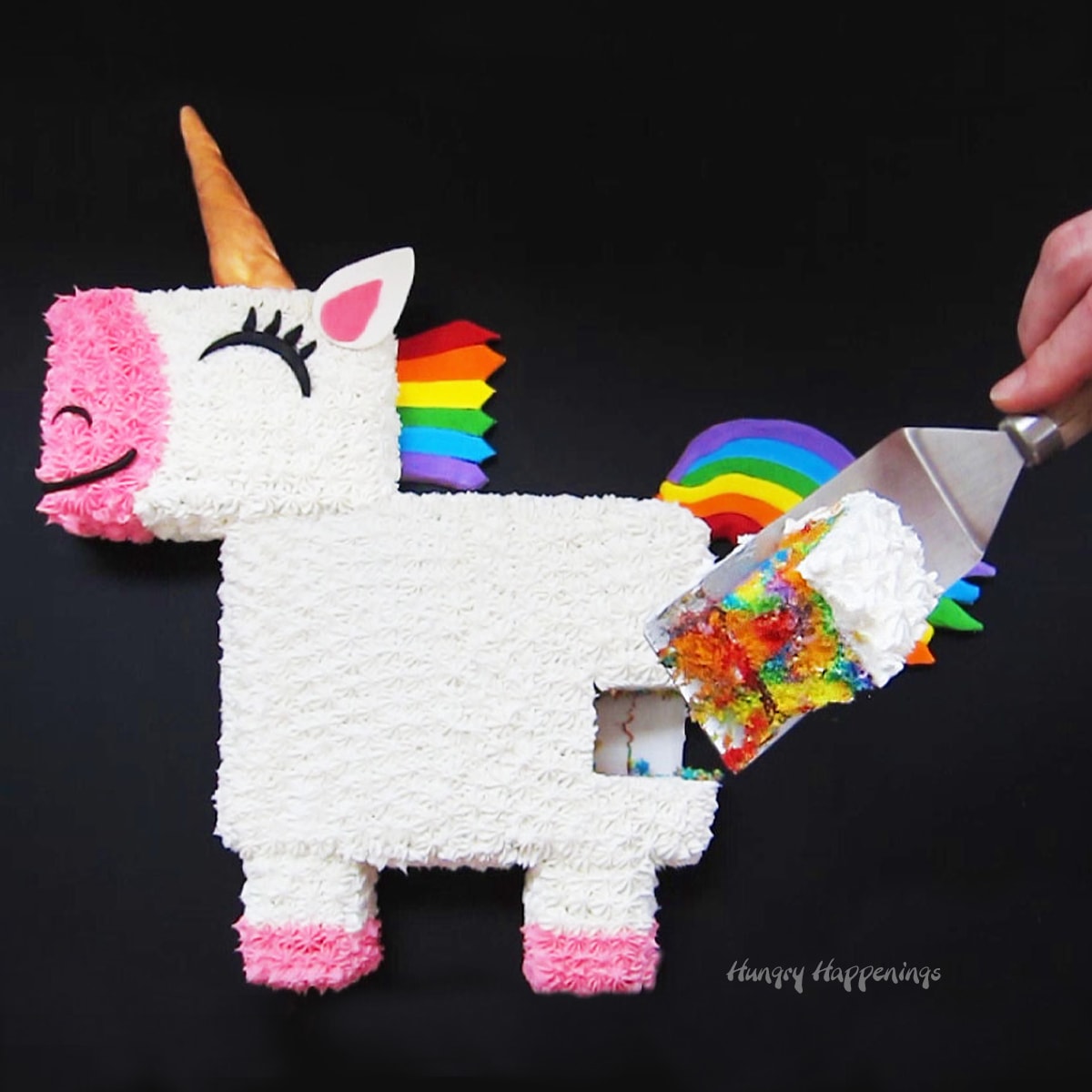 Cute unicorn cake with a piece cut out showing the rainbow cake inside.