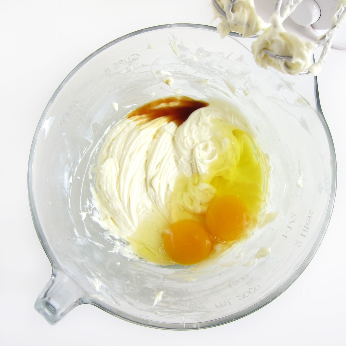 Eggs and vanilla added to creamed sugar and cream cheese in mixing bowl.
