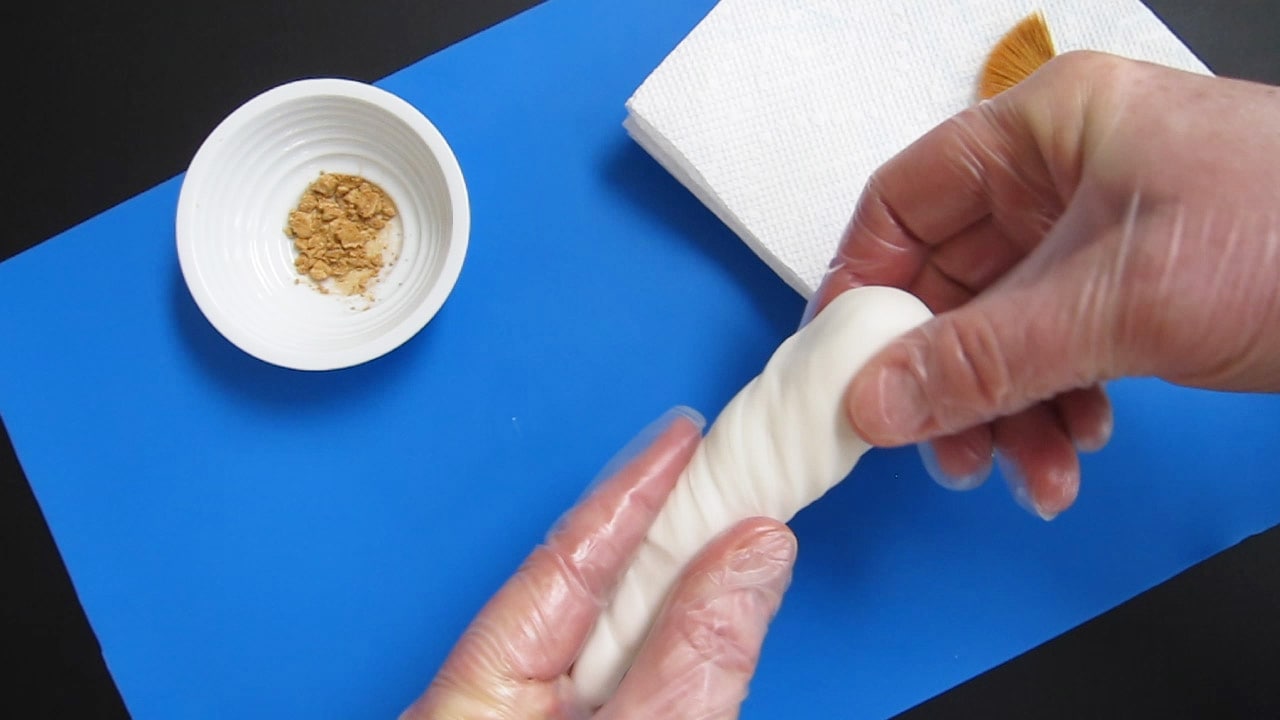 shaping and twisting white modeling chocolate into a unicorn horn.