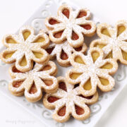 daisy-shaped linzer cookies filled with lemon curd and raspberry preserves