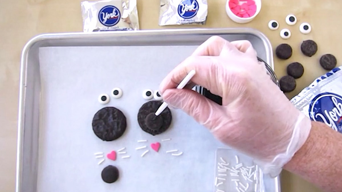 adding a dab of melted chocolate onto the mini Peppermint patty nose while creating black cats.
