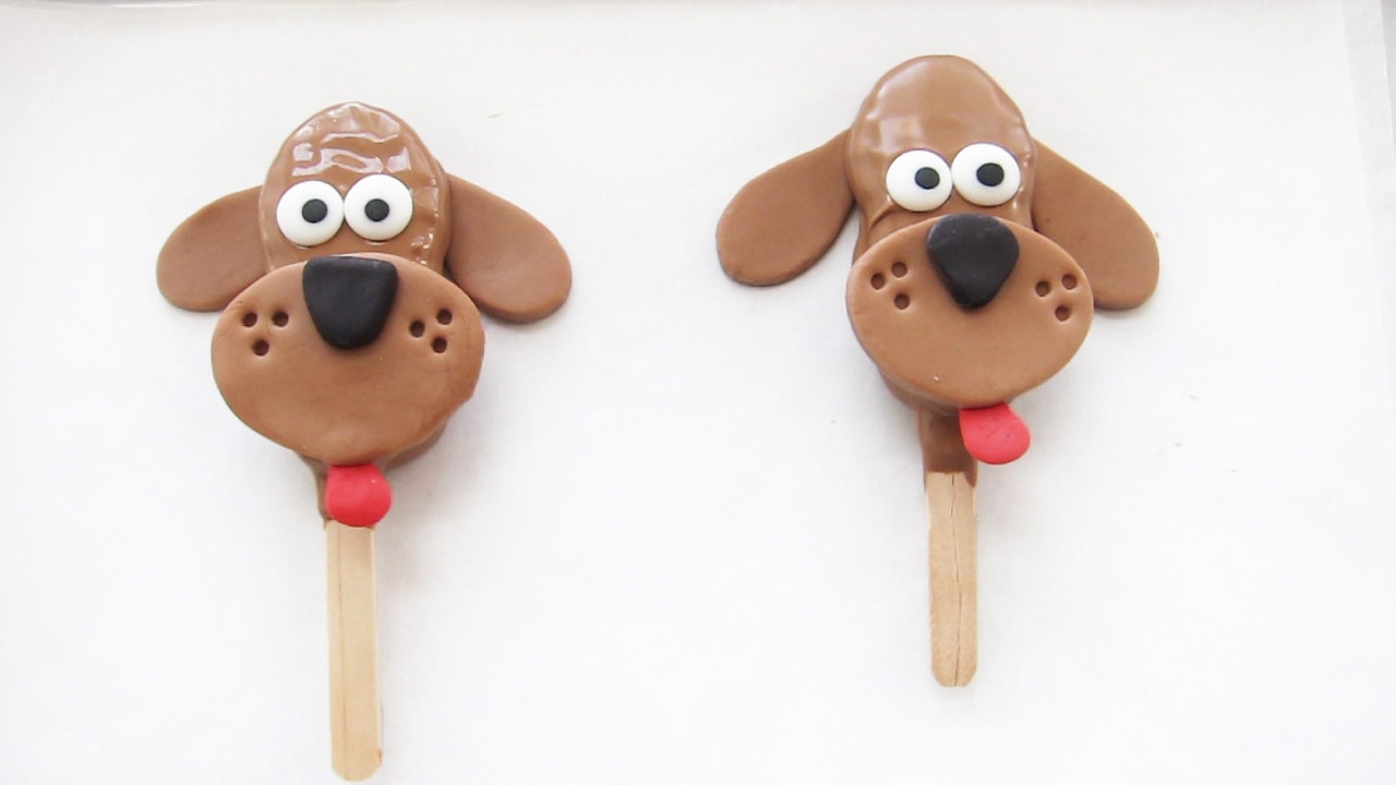 two chocolate dogs with wet melted cholate and modeling chocolate features.