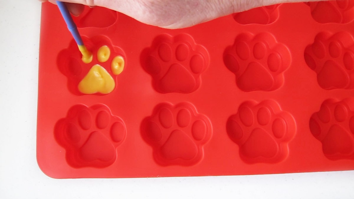 painting yellow paw pads in a silicone paw mold.