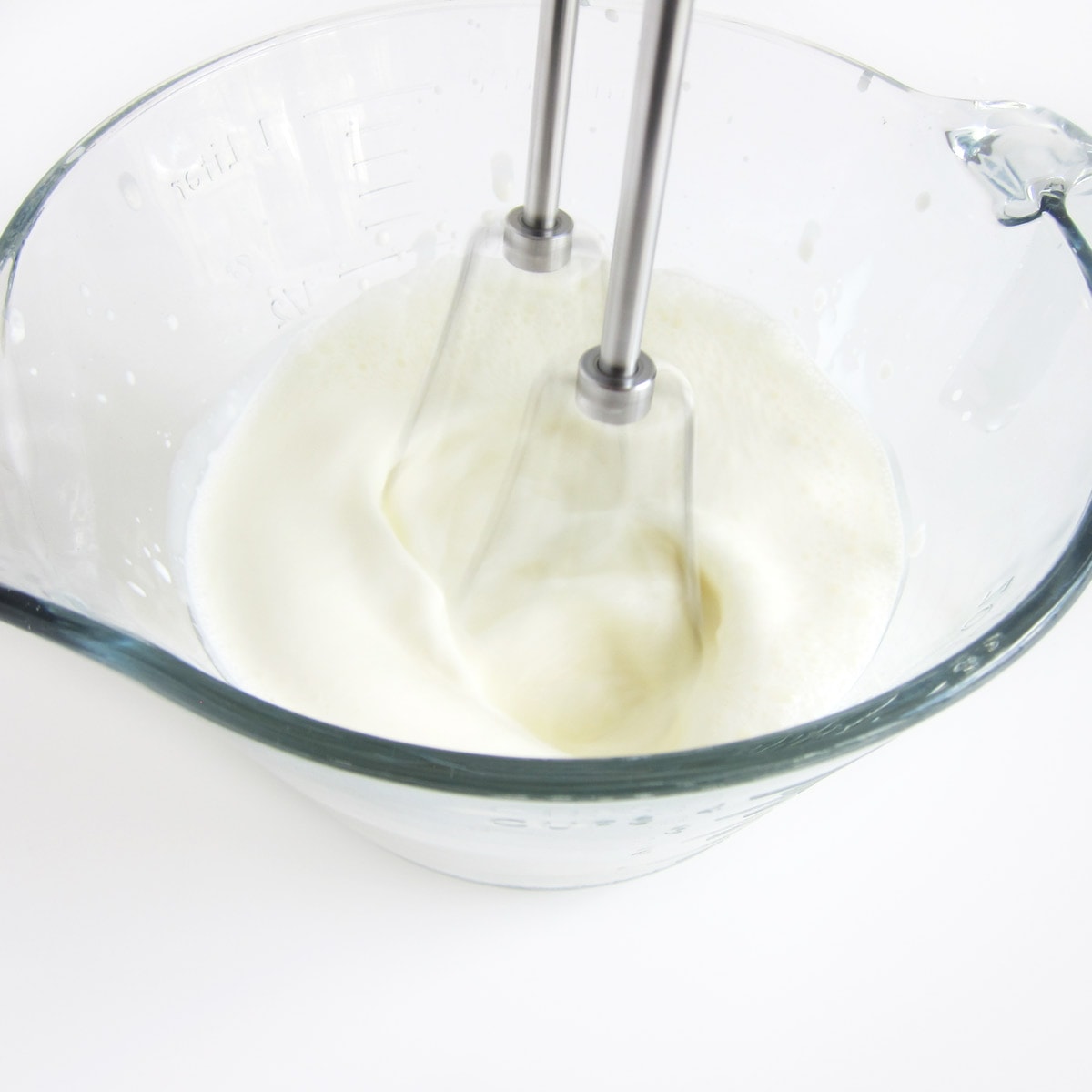 whipping cream in a mixing bowl using a hand-held mixer