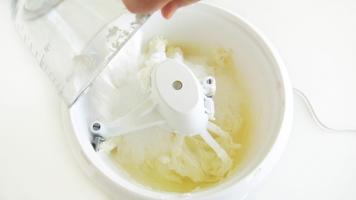 adding powdered sugar to the cream cheese in the mixing bowl.
